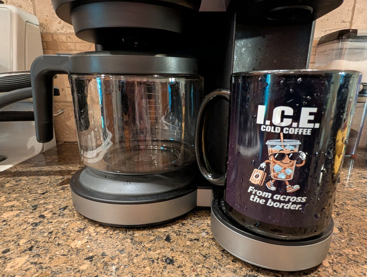 Real photo of the I.C.E. Cold Coffee From Across the Border funny black mug next to a coffee maker – Couch & Cart