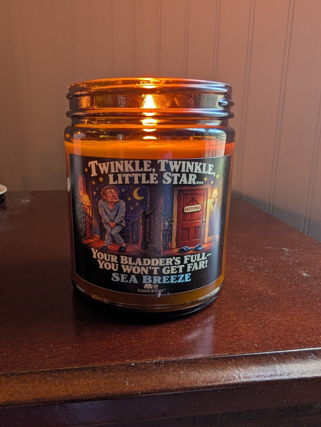 Real photo of the lit Twinkle Twinkle Little Star funny bathroom candle in an amber jar, Sea Breeze scent – Couch & Cart